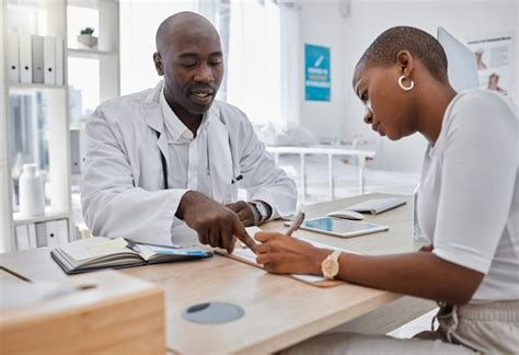 Woman Writing Signature Or Sign On Paper With A Doctor At The Hospital Man Healthcare Professional Consulting On Medical Insurance Document Or Form Discuss Surgery Compliance Together In An Office Stock Photo